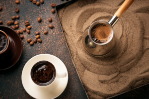 Turkish coffee roasting in sand ready to be poured into a mug.